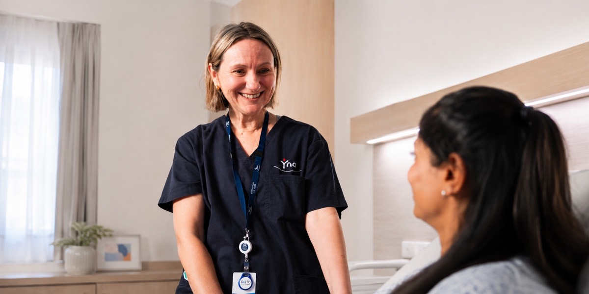 A nurse talking with a patient at their bedside