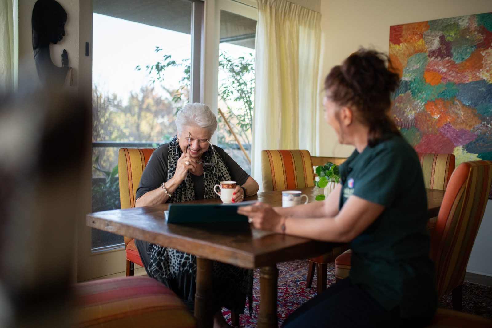 A support worker and an older client going through a plan together at the kitchen table